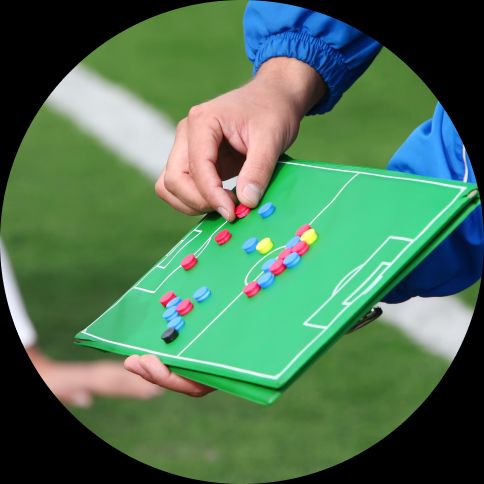 Image of a coach demonstrating a football strategy on a handheld magnetic board.