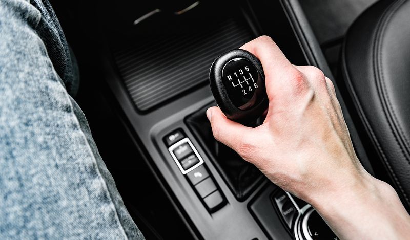 A close-up image of a hand on a manual gear stick in a car.