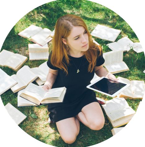 A person sitting on grass with both an e-reader and physical books, representing the choice between modern agile testing and traditional testing approaches