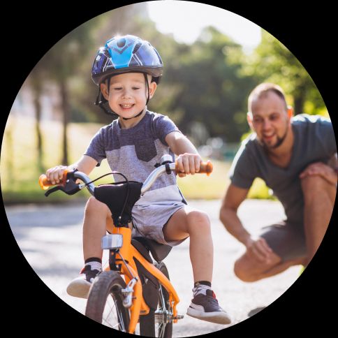 Child on a bike being taught by a parent.