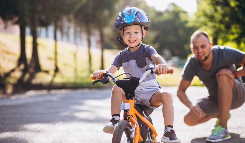 Child on a bike being taught by a parent.