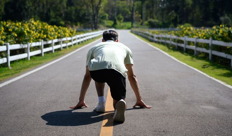 Man viewed from behind in a running stance on a street, poised to start, representing getting started with agile testing