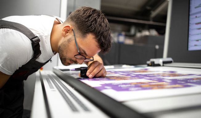 Man looking through an eye glass at something on a desk