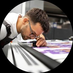 Man looking through an eye glass at something on a desk